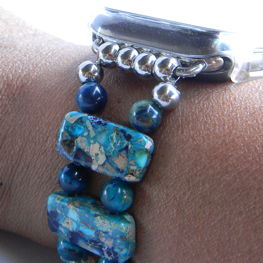 A close-up of a silver-toned bangle bracelet worn on a wrist, featuring round and rectangular turquoise-blue marbled beads with natural matrix patterns and small polished silver beads.