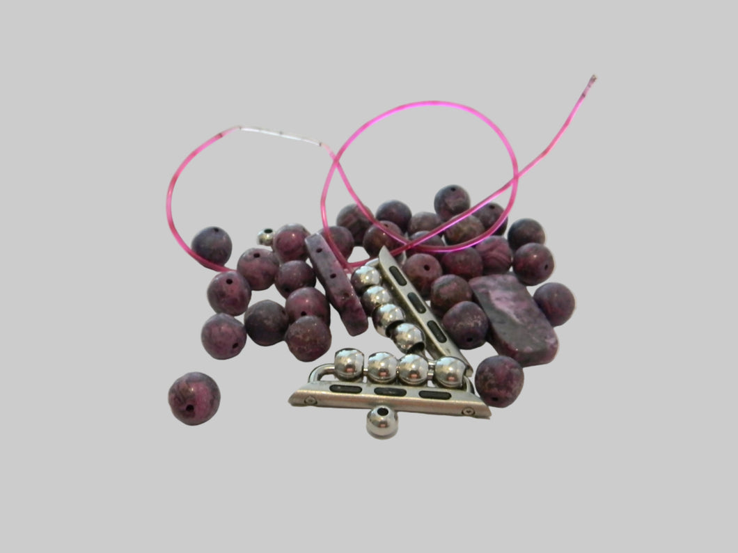 Beads and a metal tool on a light gray background